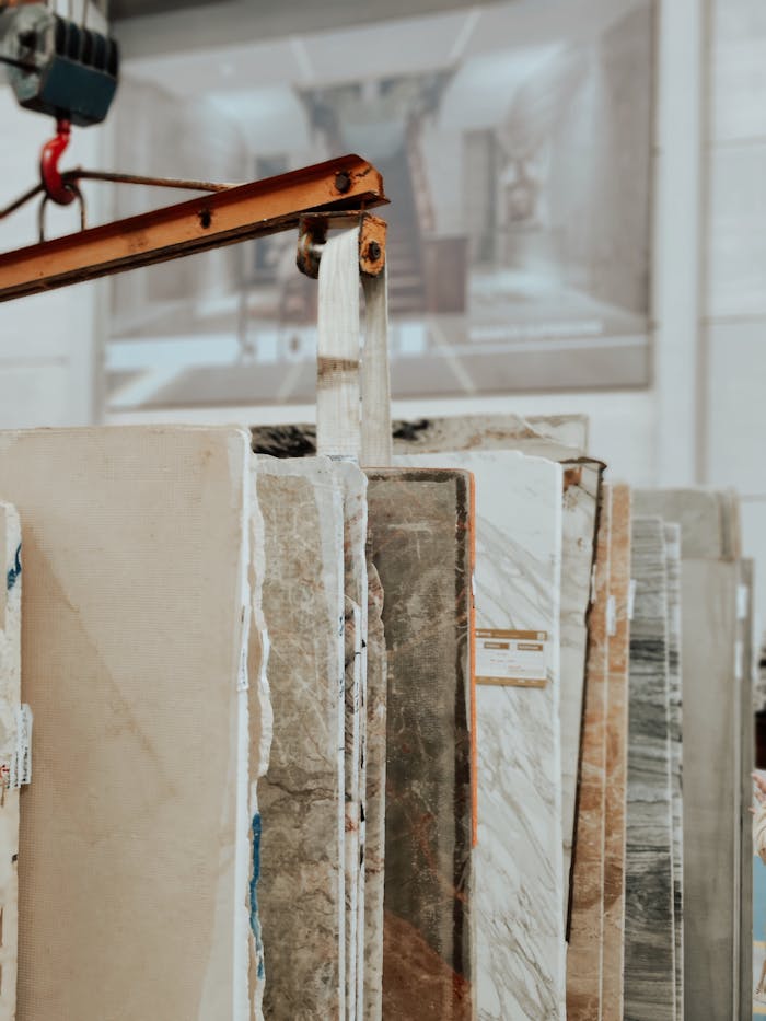 Vertical shot of marble and granite slabs with a construction hook indoors.